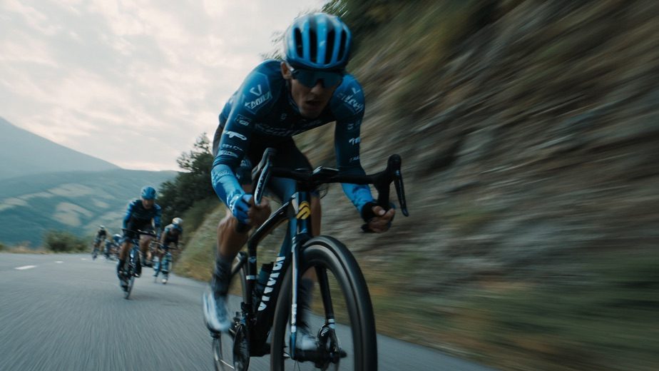 Cyclist in blue on a fast descent, eyes on the road ahead